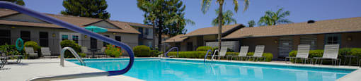 A swimming pool surrounded by a white fence and trees.