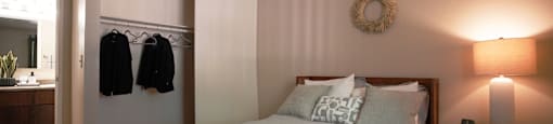 A bedroom with a bed, a wreath on the wall, and a nightstand with a lamp.