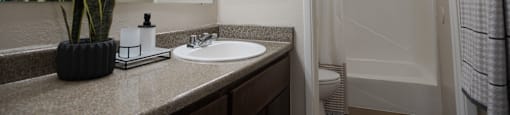 A bathroom with a sink, mirror, and shower.