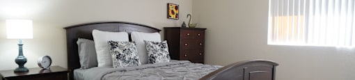 A bedroom with a bed, nightstand, and lamp.