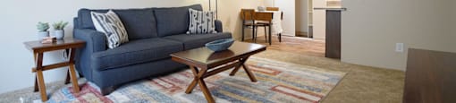 A living room with a blue couch, a wooden coffee table, and a rug.