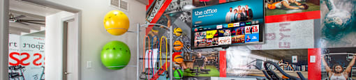 Modern apartment fitness center with entertainment TV.