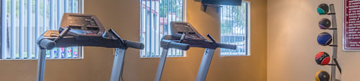 fitness center with large windows and tv and treadmills