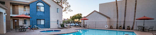 A swimming pool surrounded by a concrete floor and palm trees.