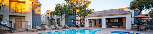 A swimming pool surrounded by a fence and chairs.