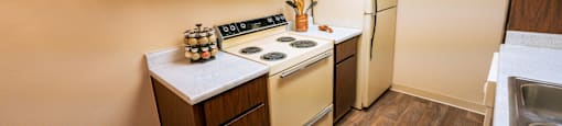A kitchen with a stove, refrigerator, and wooden cabinets.