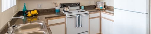 Cantera kitchen with plenty of cabinetry, sink and stove
