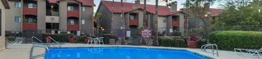 Enclave large pool view with lounging space and trees surrounding