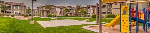 Desert Sands playground and basketball court surrounded by green grass.