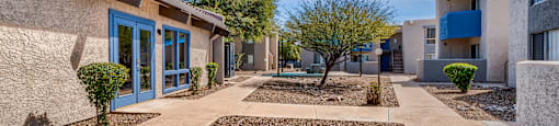 a building with blue doors and a courtyard with rocks and trees