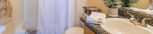 bathroom with updated sink and tub shower combo with white curtains