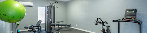 a gym with exercise equipment and a green ball in the corner