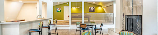 a community clubhouse with tables and chairs, bar top seating and a fireplace