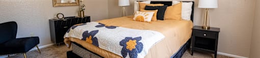 A bedroom with a bed, chair, and two lamps.