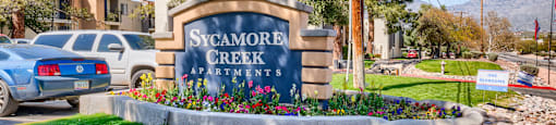A sign for Sycamore Creek Apartments is in front of a grassy area.