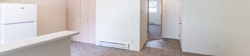 a kitchen and living room with white walls and carpet