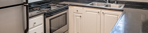 a kitchen with white cabinets and black countertops