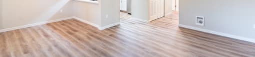 an empty living room and kitchen with a wood floor
