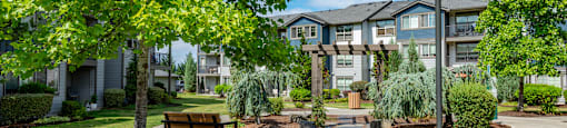 a park with trees and a bench in front of an apartment building