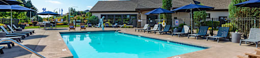our resort style swimming pool is surrounded by lounge chairs and umbrellas