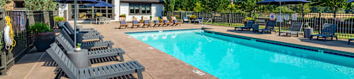 our resort style swimming pool with lounge chairs and umbrellas