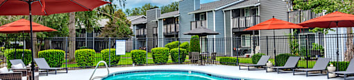 a swimming pool with umbrellas in front of apartment buildings