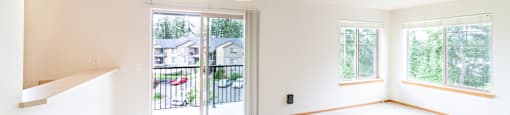 an empty living room with a sliding glass door and a balcony