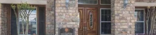 A stone building with a brown door and windows.