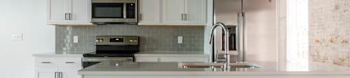 A kitchen with white cabinets and a white island.