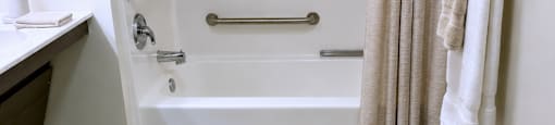 A white bathroom with a shower and a towel hanging on the wall.