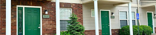 the front of a gray house with green doors