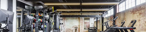 a gym with weights and cardio machines and a brick wall at The Mill at Prattville, Prattville, AL