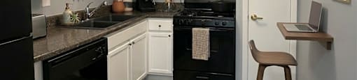 A kitchen with black appliances and white cabinets.