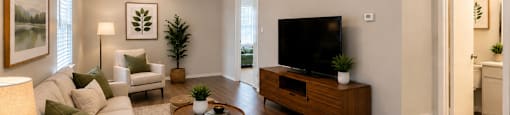 A living room with a white couch, a coffee table, a television, and a potted plant.