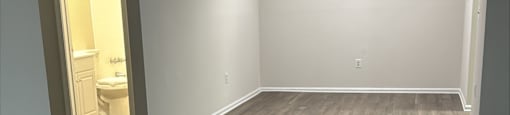 A room with wooden flooring and a doorway leading to another room.