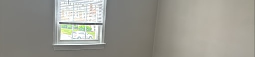 A room with a window and wooden flooring.