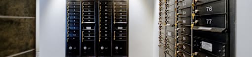 A wall of black mailboxes with gold locks and numbers on them.
