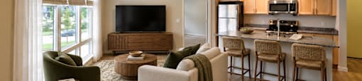 A modern living room with a television, sofas, and a kitchen area in the background.