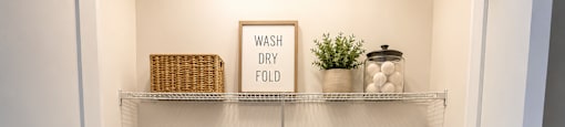 A laundry room with a basket and a sign that says "Wash Dry Fold".