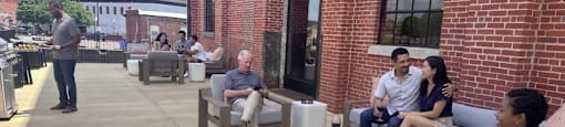 A group of people are sitting on a patio outside a brick building.