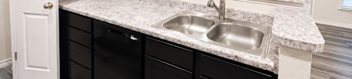 A kitchen with black cabinets and a marble countertop.