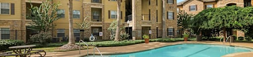 A swimming pool in front of a building with palm trees.