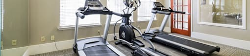 A home gym with a treadmill, elliptical trainer, and stationary bike.
