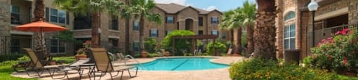 A pool surrounded by palm trees and a patio area with chairs.
