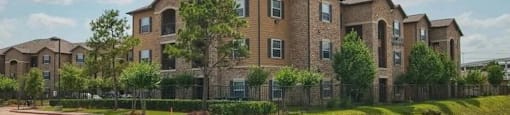 A large brick apartment complex with a parking lot in front.
