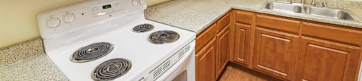 A white stove and microwave in a kitchen with wooden cabinets.