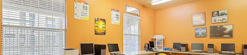 A classroom with orange walls, a white table, and multiple chairs.
