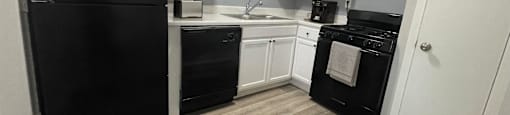 a kitchen with black appliances and white cabinets at The Junction, Memphis, TN