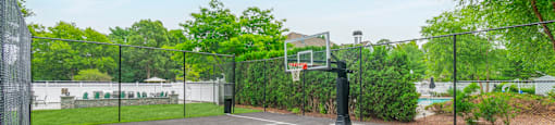 Outdoor basketball court with chain link fencing at Woodlands at Abington Station Apartments, Abington, MA 2351