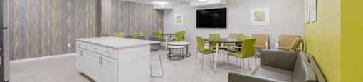 A Community Room with a table and chairs and a kitchen at North Stoughton Village Apartments in Stoughton, MA